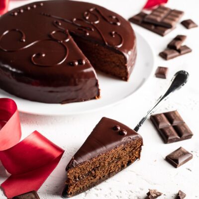 Sacher con glassa lucida al cioccolato e una fetta tagliata che rivela lo strato di albicocca