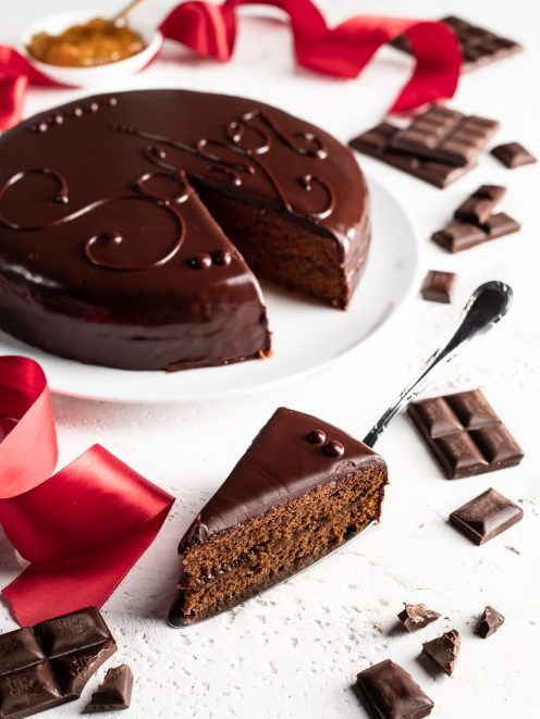 Sacher con glassa lucida al cioccolato e una fetta tagliata che rivela lo strato di albicocca