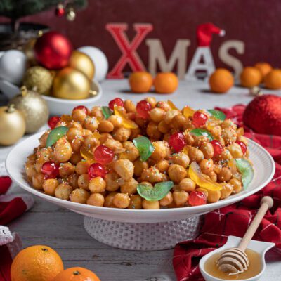 Struffoli glassati al miele con frutta candita colorata e codette, disposti a corona