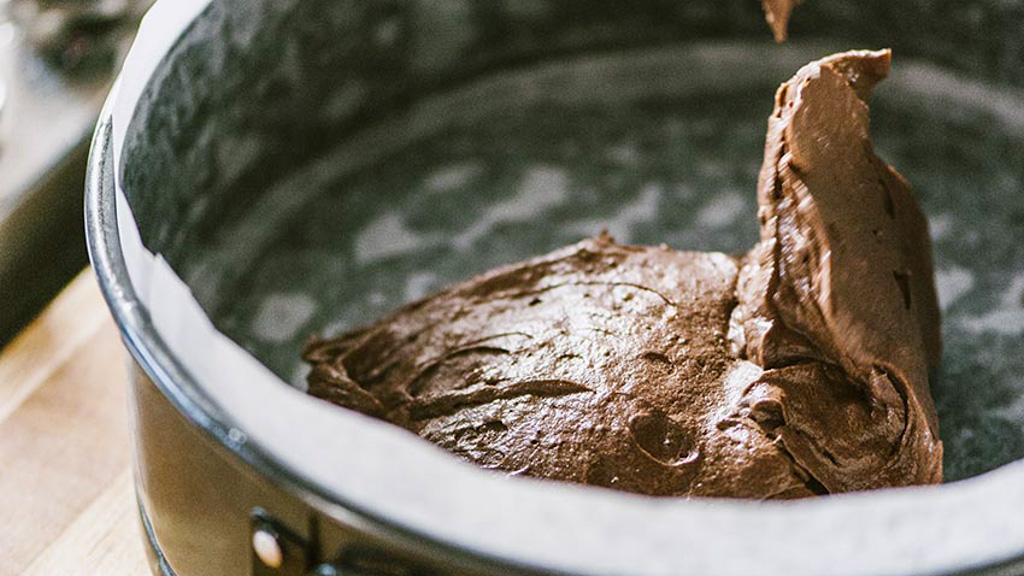 Impasto al cioccolato versato in una tortiera foderata con carta forno