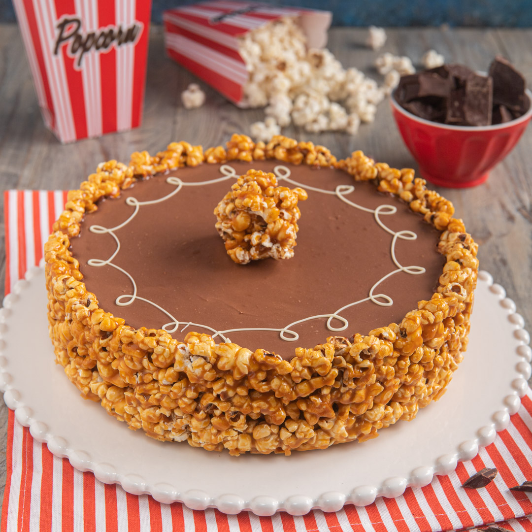 Torta decorata con glassa al cioccolato, bordo di popcorn caramellati e ciuffo centrale