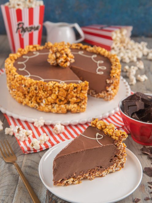 Torta popcorn con mousse al cioccolato: una fetta rivela la crema densa, con bordo di popcorn caramellati