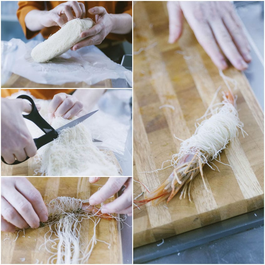 Gambero avvolto nei fili di pasta kataifi tagliati e arrotolati sul tagliere di legno