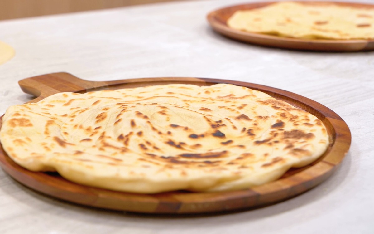 Piadine romagnole cotte con macchie di cottura, appoggiate su tagliere rotondo