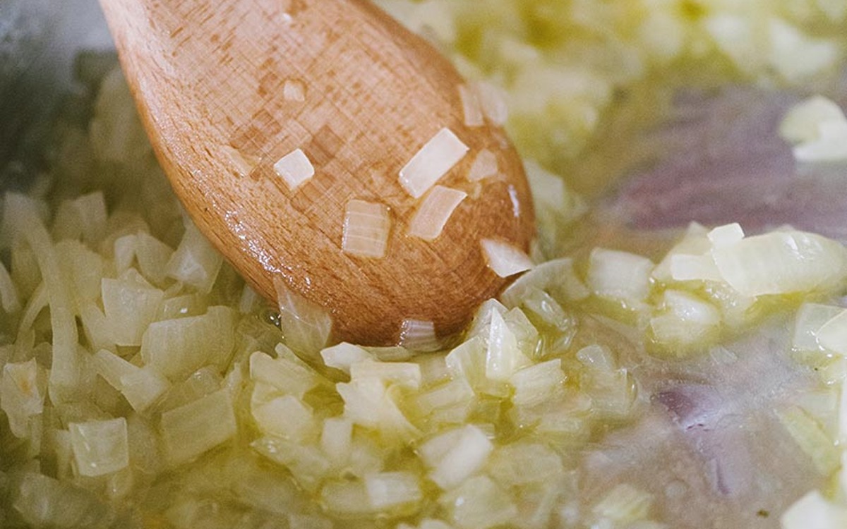 Cipolla tritata che appassisce mescolata con un cucchiaio di legno