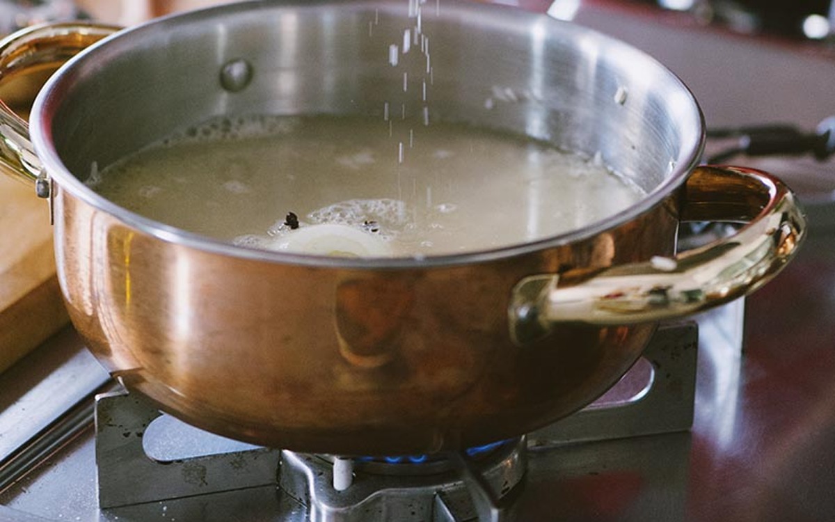 Acqua bollente versata sul riso in cottura sul fuoco vivo