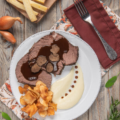 Arrosto di bue grasso alle erbe con Barolo, fette di tartufo nero, fonduta e chips di topinambur