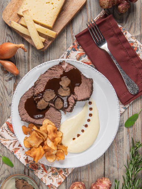 Arrosto di bue grasso alle erbe con Barolo, fette di tartufo nero, fonduta e chips di topinambur