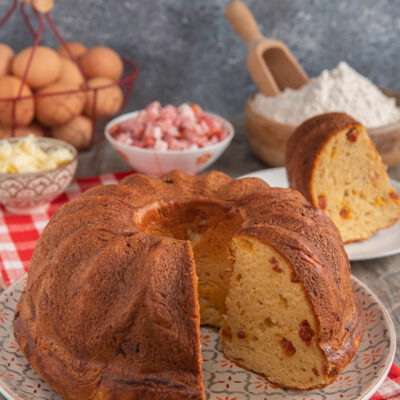 Babà rustico salato con una fetta tagliata che rivela l'impasto soffice con pezzetti di salumi