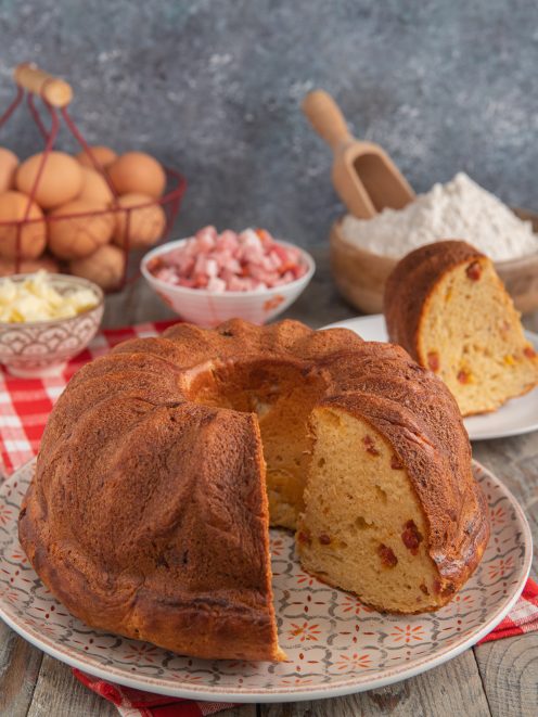 Babà rustico salato con una fetta tagliata che rivela l'impasto soffice con pezzetti di salumi