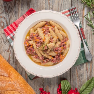Capunsei mantovani conditi con ragù bianco di cotechino e carote, guarniti con un rametto di rosmarino