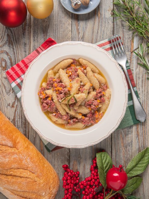 Capunsei mantovani conditi con ragù bianco di cotechino e carote, guarniti con un rametto di rosmarino