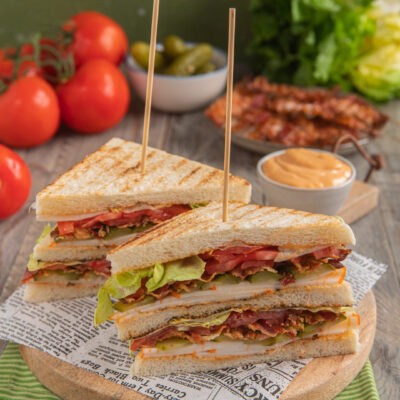 Club sandwich tagliato a triangoli con bacon, pomodoro, lattuga e salsa, fermato da stecchini
