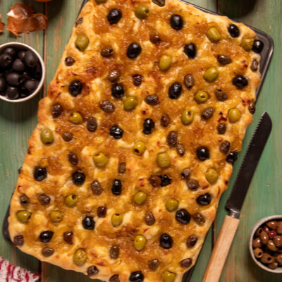 Focaccia alle 3 olive e cipolle dorata in teglia, ricoperta di olive verdi, nere e taggiasche