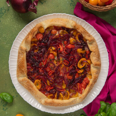 Galette salata con bordo di sesamo, pomodorini colorati e cipolla rossa caramellata
