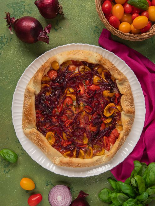 Galette salata con bordo di sesamo, pomodorini colorati e cipolla rossa caramellata