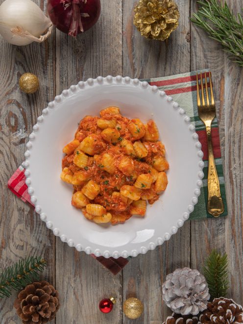 Gnocchi con sugo di faraona conditi con erbe fresche tritate, serviti in abbondante porzione