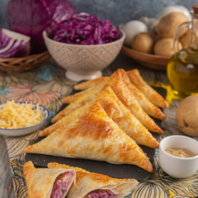 Hand pies vegetariane triangolari di pasta sfoglia con ripieno di cavolo rosso e formaggio filante