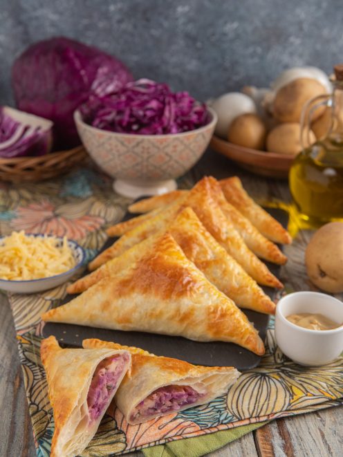 Hand pies vegetariane triangolari di pasta sfoglia con ripieno di cavolo rosso e formaggio filante