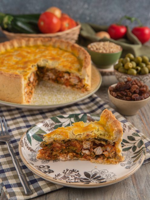 Fetta di impanata di pesce spada con ripieno di pomodoro e zucchine, torta intera sullo sfondo