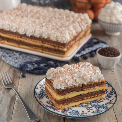 Mattonella di biscotti e cioccolato a strati con crema pasticcera e ciuffi di panna cacao