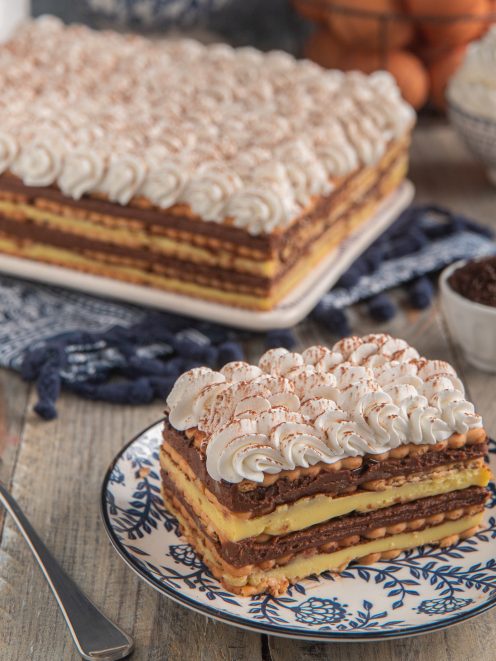 Mattonella di biscotti e cioccolato a strati con crema pasticcera e ciuffi di panna cacao