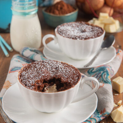 Mug cake al cioccolato in tazza con cuore di cioccolato bianco e zucchero a velo