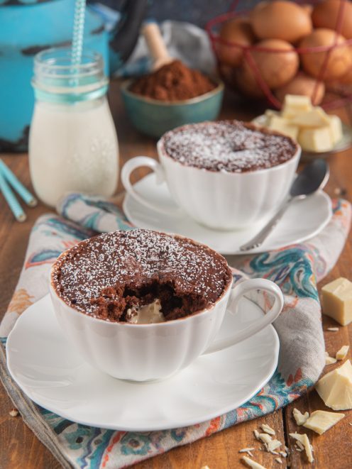 Mug cake al cioccolato in tazza con cuore di cioccolato bianco e zucchero a velo