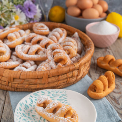 Nacatole calabresi fritte spolverizzate di zucchero a velo, servite in un cesto e su un piattino