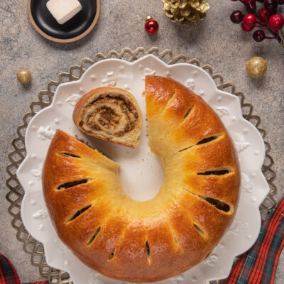 Pan brioche di Natale a corona dorata con una fetta tagliata che rivela il ripieno a spirale