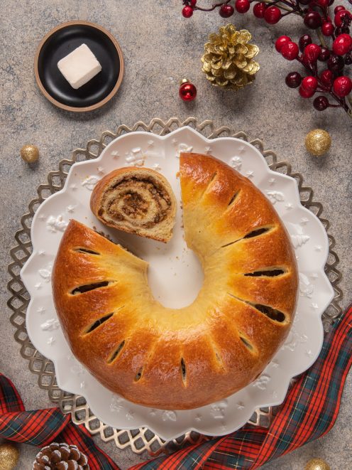 Pan brioche di Natale a corona dorata con una fetta tagliata che rivela il ripieno a spirale