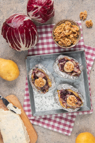 Patate al cartoccio ripiene di radicchio, gorgonzola e noci servite aperte su teglia