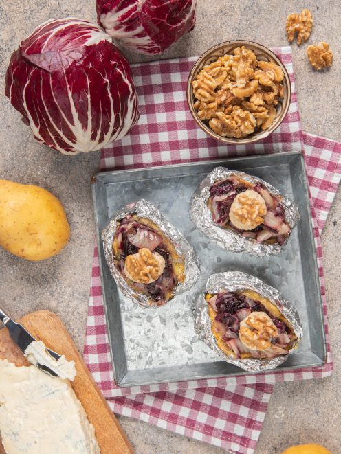 Patate al cartoccio ripiene di radicchio, gorgonzola e noci servite aperte su teglia
