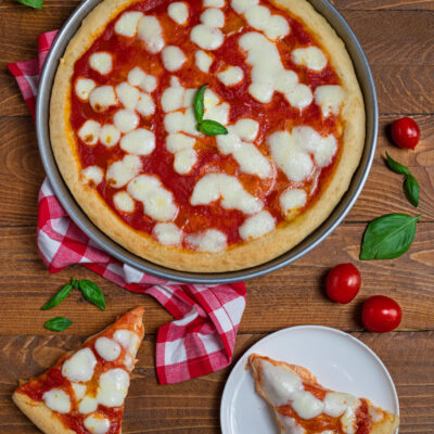 Pizza margherita con pomodoro, mozzarella a bocconcini e basilico fresco, servita a fette