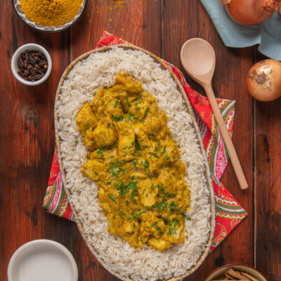 Pollo al curry servito su riso pilaf, guarnito con prezzemolo fresco tritato