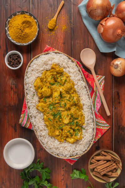 Pollo al curry servito su riso pilaf, guarnito con prezzemolo fresco tritato