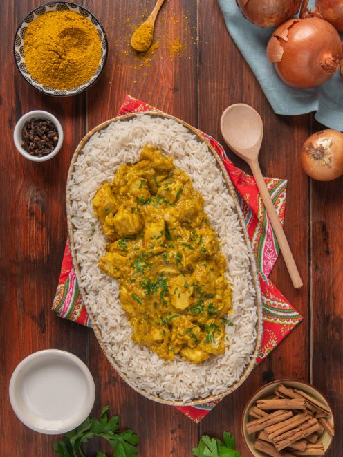 Pollo al curry servito su riso pilaf, guarnito con prezzemolo fresco tritato