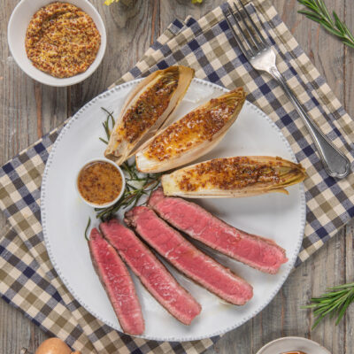 Tagliata di vitello al rosa con indivia gratinata alla senape e miele, servita con salsa a parte