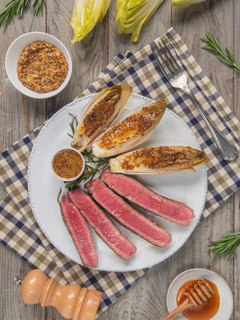 Tagliata di vitello al rosa con indivia gratinata alla senape e miele, servita con salsa a parte