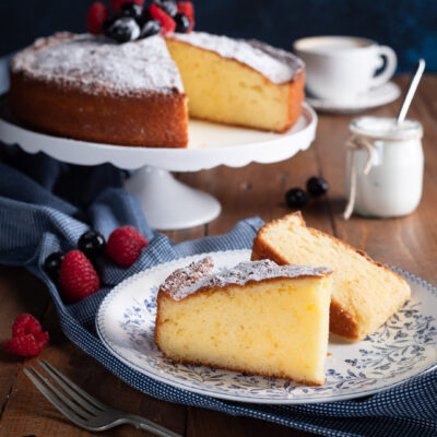 Torta allo yogurt in fetta con zucchero a velo, fragoline di bosco e mirtilli