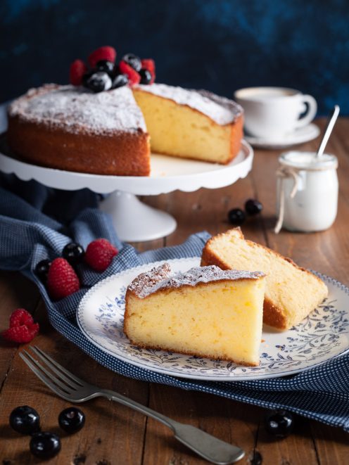 Torta allo yogurt in fetta con zucchero a velo, fragoline di bosco e mirtilli