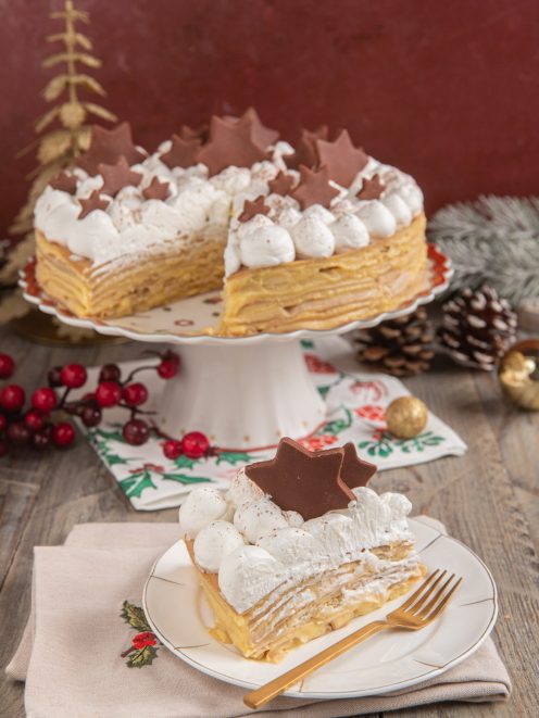Torta di crepes farcita a strati con panna a ciuffi e stelline di cioccolato, fetta servita a parte