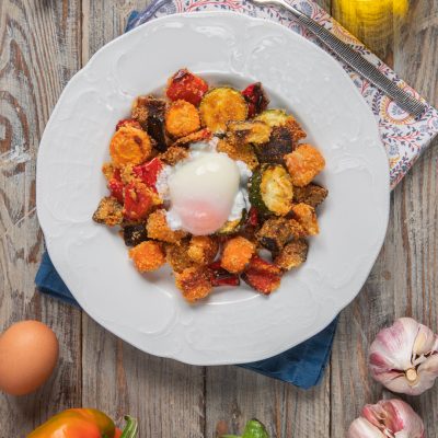 Uova poché adagiate su verdure gratinate con melanzane, zucchine, carote e peperoni