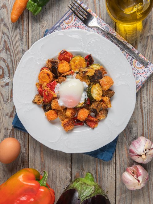 Uova poché adagiate su verdure gratinate con melanzane, zucchine, carote e peperoni