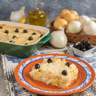 Bacalhau com nata a fette servito nel piatto con guarnizione di olive nere