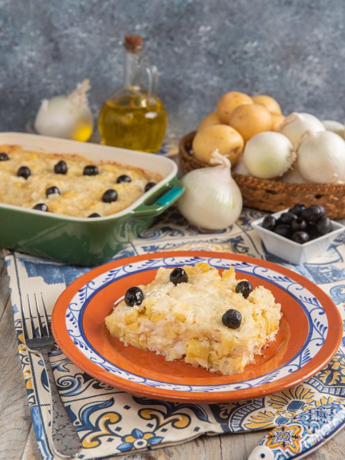 Bacalhau com nata a fette servito nel piatto con guarnizione di olive nere