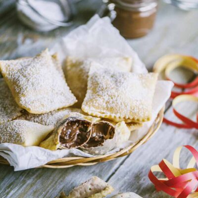 Bugie ripiene di cioccolato spolverate di zucchero a velo, aperte a mostrare il cuore morbido