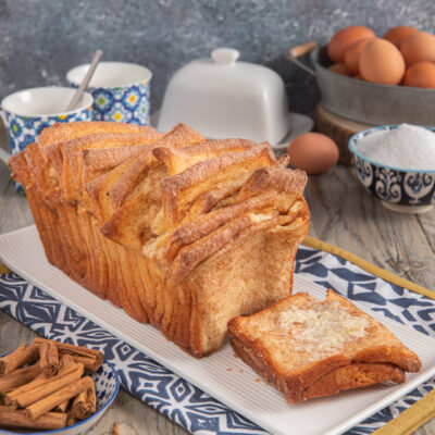 Cinnamon sugar pull-apart bread a strati dorati con una fetta staccata a fianco