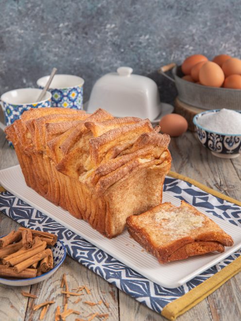 Cinnamon sugar pull-apart bread a strati dorati con una fetta staccata a fianco