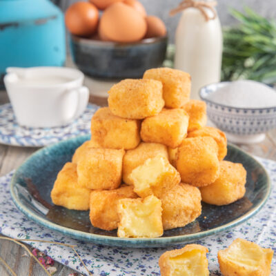 Crema fritta impilata a piramide, con uno spezzato che mostra il cuore morbido di crema pasticcera